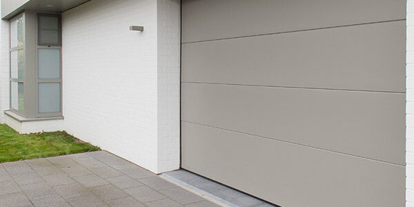 Portes de garage sectionnelle électrique grise sur une maison blanche à Namur