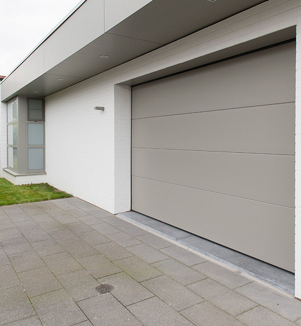 Portes de garage sectionnelle électrique grise sur une maison blanche à Namur